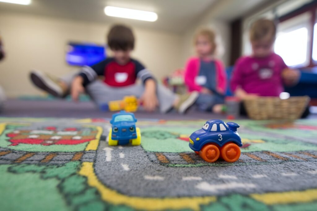 Photos de petite voiture sur un tapis d'enfant. Enfants en flou d'arrière plans.